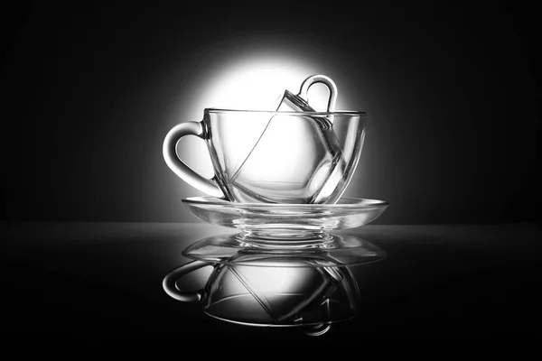 Duas xícaras de chá transparentes feitas de vidro em uma mesa com reflexão. Produtos de cozinha preto e branco . — Fotografia de Stock