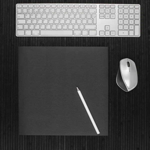 workspace desk with white keyboard, computer mouse and pencil copy space background black