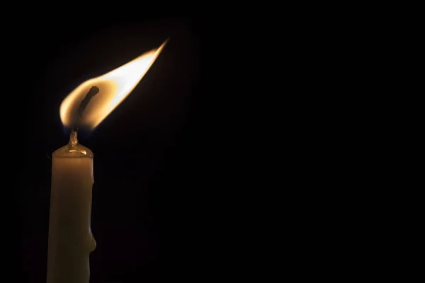 Uma vela acesa em um fundo escuro . — Fotografia de Stock