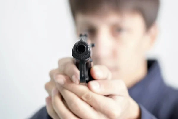 A young man aiming from a pistol. Selected focus. — Stock Photo, Image