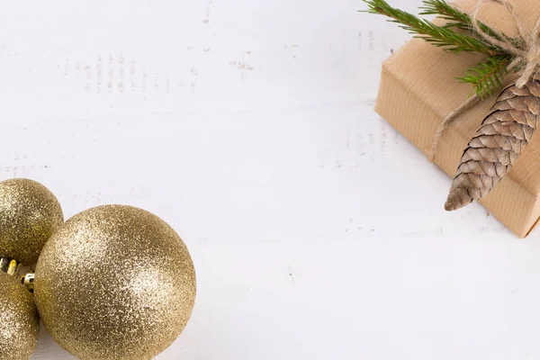 Geschenkverpakking in Eco stijl. Samenstelling met een geschenk doos, gouden kerstballen. — Stockfoto