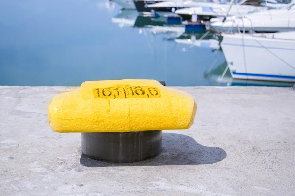 Mooring bollard on a pier with docked yacht on the background — Stock Photo, Image