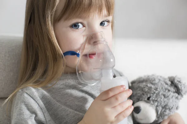 Kleines Mädchen beim Inhalieren mit Vernebler zu Hause. Kind Asthma Inhalator Inhalationsvernebler Dampf krank Husten Konzept Stockfoto