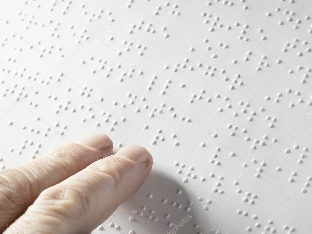 Hand of a blind person reading some braille text touching the relief. Empty copy space for Editor