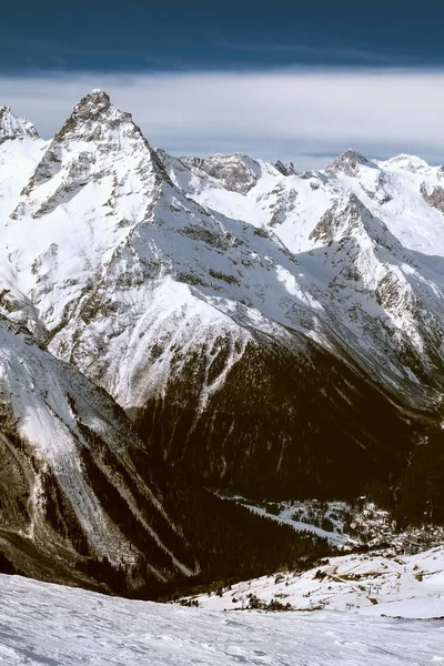 Snowy mountains in clouds at sun day. Caucasus Mountains, mount Belalakaya, ski resort Dombay. Vertical — Stock Photo, Image