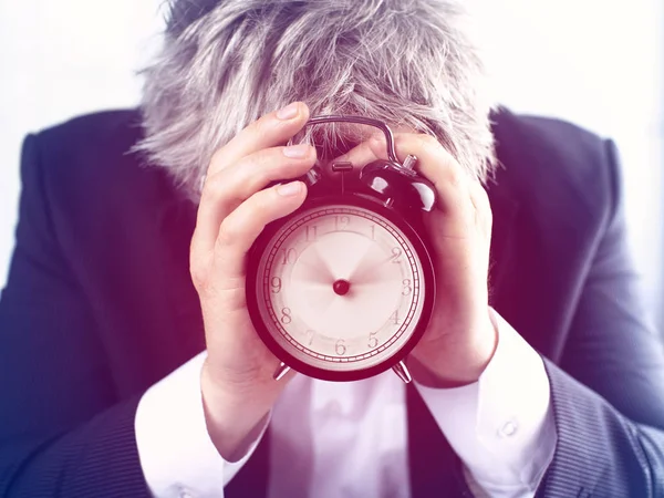 白い背景の目覚まし時計の後ろに顔を隠している男 時間管理の考え方 — ストック写真