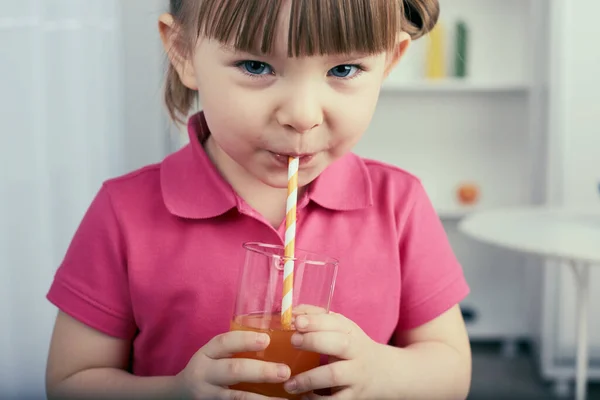 Menina bonito bebe suco de laranja em casa — Fotografia de Stock