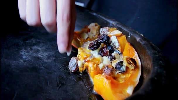 Pedaço de abóbora cozida no forno com frutos e nozes - uma gilr toma umas uvas secas — Vídeo de Stock
