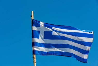 Mavi gökyüzüne karşı gelişen Yunan bayrağı 