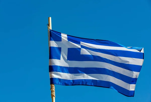 在蓝天的映衬下升起希腊国旗 免版税图库照片