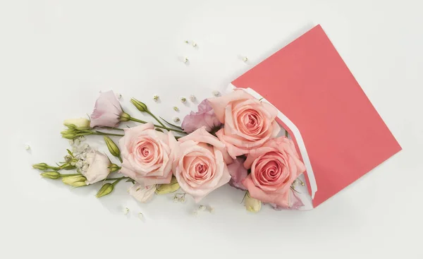 Çiçek teslimatı hediyesi olarak zarftan çıkan pembe güller.