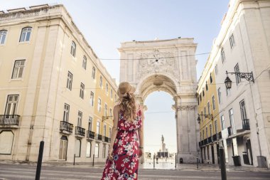 Kırmızı üniformalı ve şapkalı genç sarışın bir turist bir Avrupa şehrinde şehir merkezini keşfediyor.