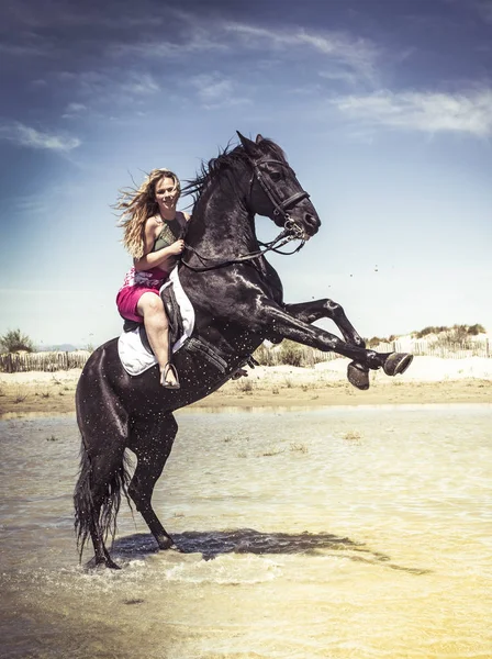在海滩上骑着她的黑种马的女人 — 图库照片