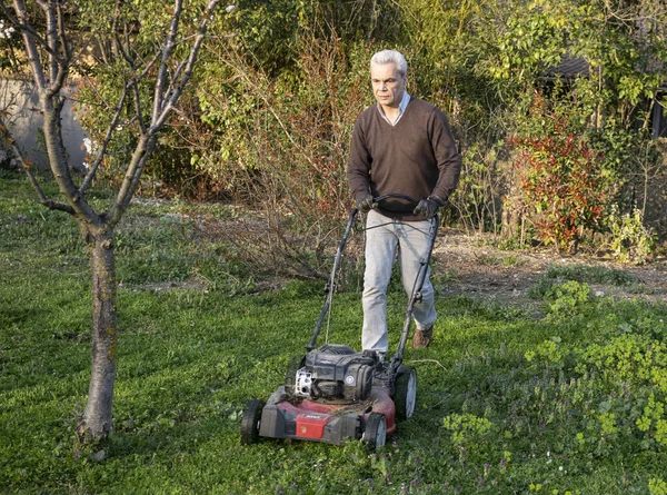 春天的时候 他带着割草机在自家的花园里 — 图库照片