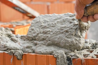 Duvarcı işçisi dış duvara tuğla döşüyordu.