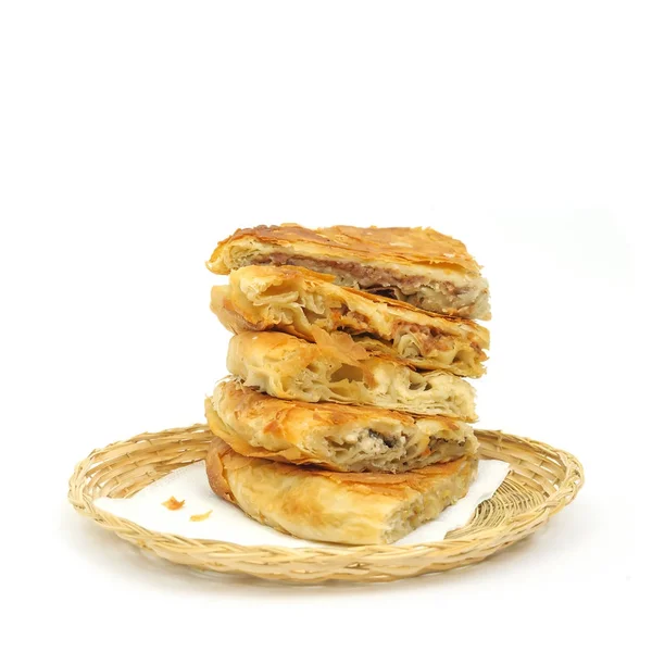 Γεύση ποικιλία στοίβα τραγανό Burek ή πίτες σε μια χαρτοπετσέτα σε ένα καλάθι λυγαριά ή ψωμί πάνω από το λευκό φόντο — Φωτογραφία Αρχείου