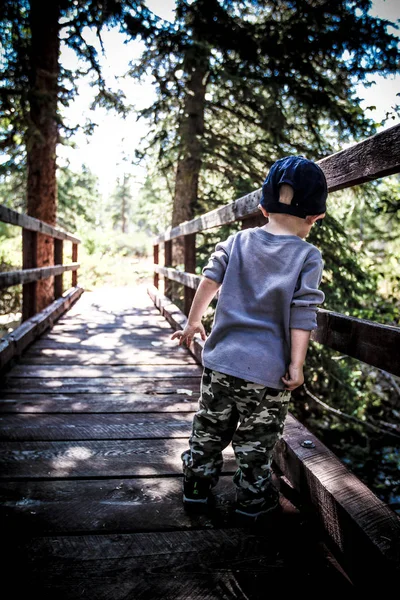 Little boy standing looking over bridge — Stock Photo, Image