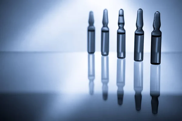 Medyczne ampułki do wstrzykiwań na białym tle na niebieskim tle — Zdjęcie stockowe