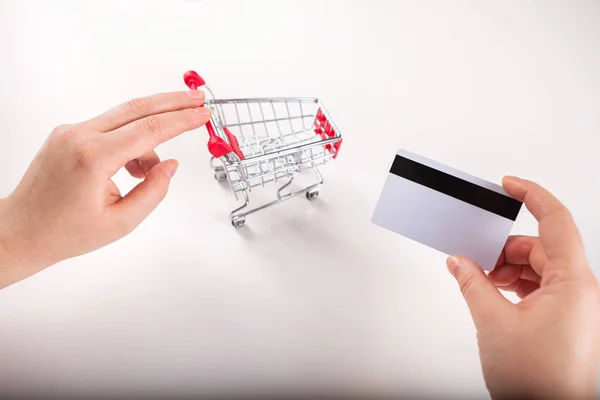 Bank card nearby a laptop and mini shopping cart on white backg — Stock Photo, Image