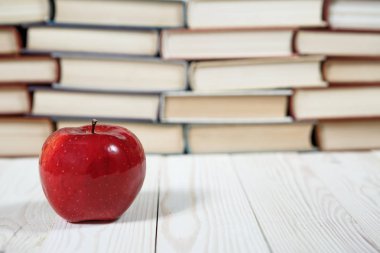 Masada bir yığın kitap ve elma var.