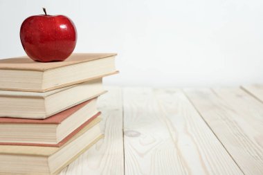 Masada bir yığın kitap ve elma var.