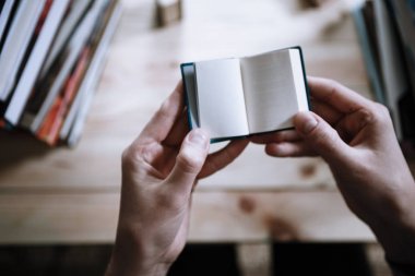 Kütüphanede büyük kitaplar arasında minyatür kitap okurken erkek