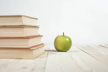 Masada bir yığın kitap ve elma var.