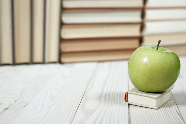 Stack of books and apple on the table