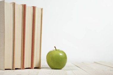 Masada bir yığın kitap ve elma var.