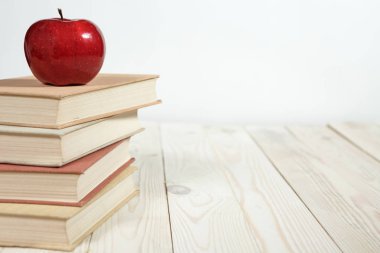 Masada bir yığın kitap ve elma var.