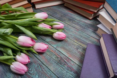 Ahşap arka plan kitapları ile pembe laleler