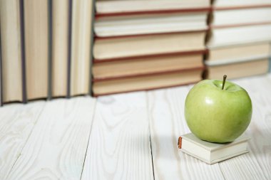 Masada bir yığın kitap ve elma var.
