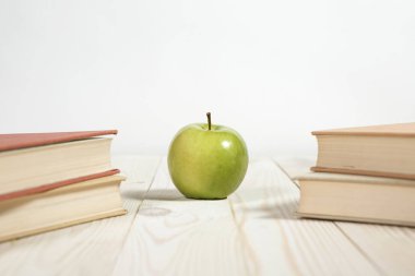 Masada bir yığın kitap ve elma var.