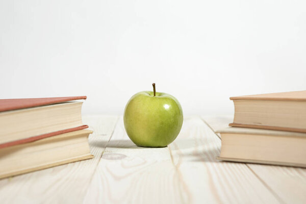 Stack of books and apple on the table