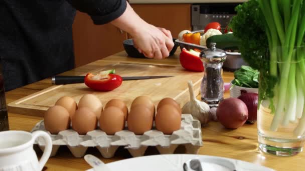 Kvinnan med kniv skär mogen, röd peppar för sallad. — Stockvideo