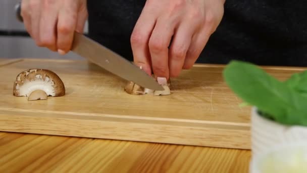 Женщина режет грибы на деревянной доске — стоковое видео
