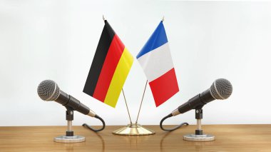 Mikrofonlar ve bayraklar, odaklanmamış arka planda bir masanın üzerinde.