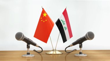 Mikrofonlar ve bayraklar, odaklanmamış arka planda bir masanın üzerinde.