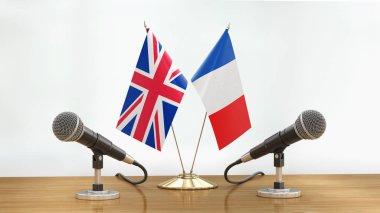 Mikrofonlar ve bayraklar, odaklanmamış arka planda bir masanın üzerinde.