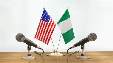 Mikrofonlar ve bayraklar, odaklanmamış arka planda bir masanın üzerinde.