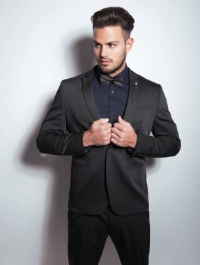 Gri arka planda takım elbiseli yakışıklı bir genç. İş adamı