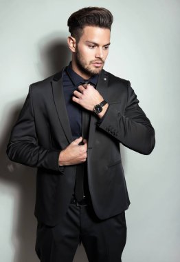 Gri arka planda takım elbiseli yakışıklı bir genç. İş adamı