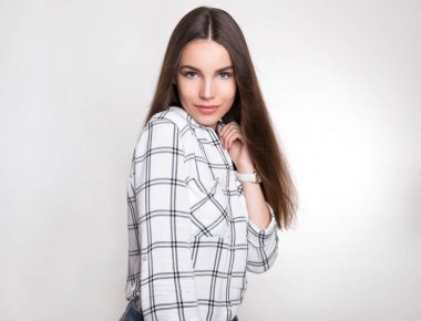 Uzun kahverengi saçlı, kol saati takan güzel bir genç kadın.