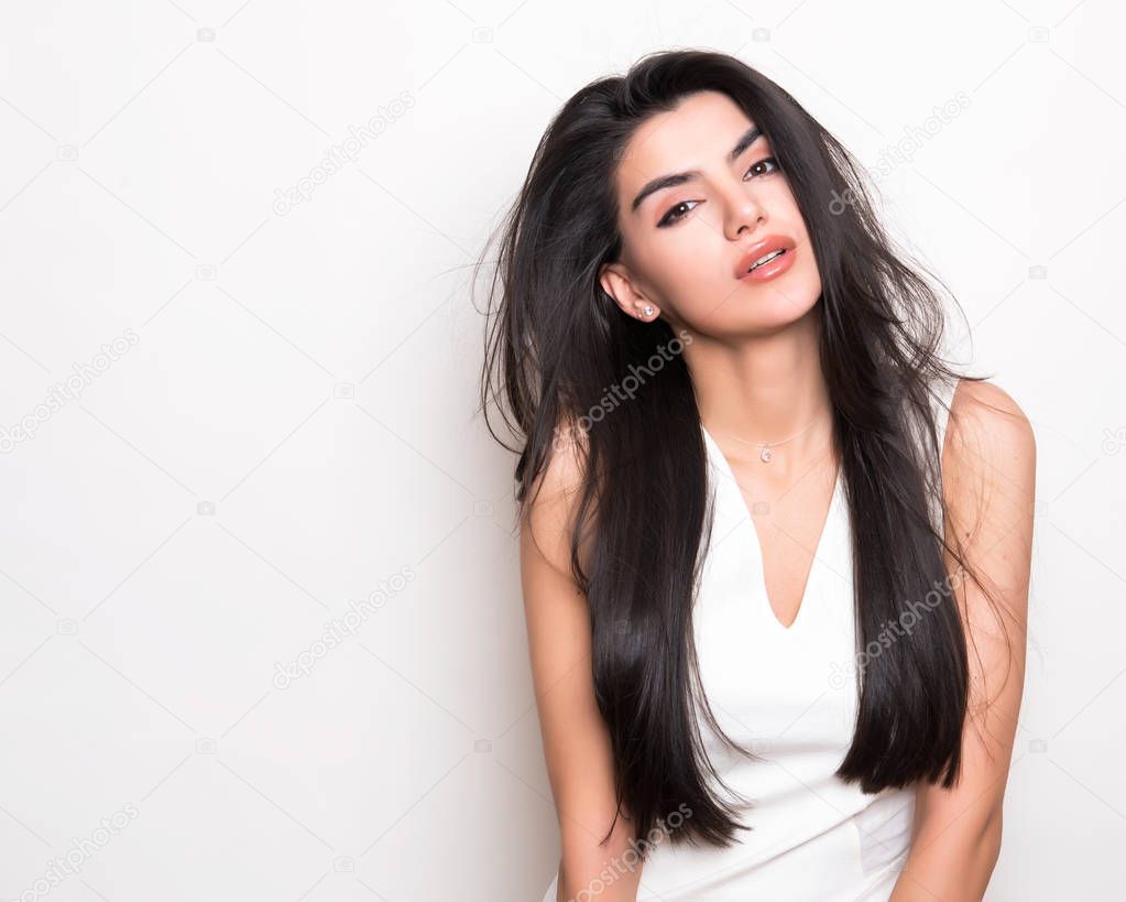 beautiful young woman with long black hair wearing dress and posing on white background