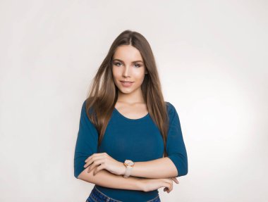 Uzun kahverengi saçlı, kol saati takan ve gri arka planda fotokopi aletiyle poz veren güzel bir kadın.