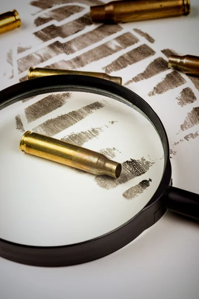 Magnifying glass with bullet shells on footprint — Stock Photo, Image