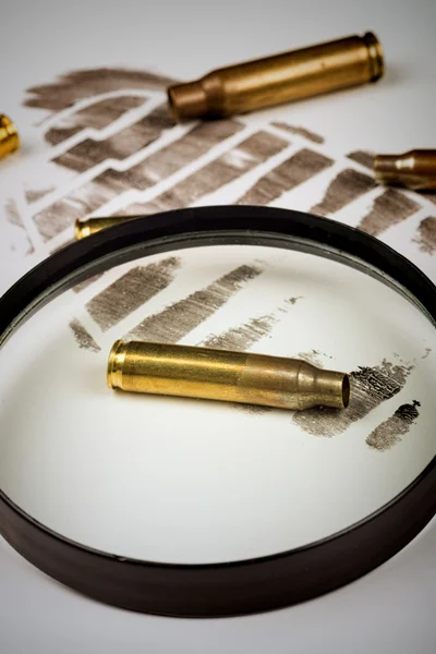 Magnifying glass with bullet shells on footprint — Stock Photo, Image