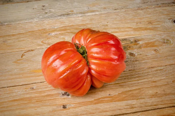 Tomate enrugado em fundo de madeira — Fotografia de Stock