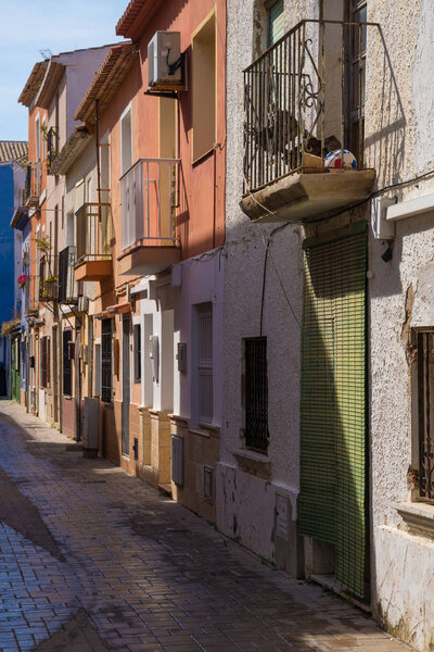 Denia fishing quarter street with colorful Mediterranean old town houses and cobbelstone pavement