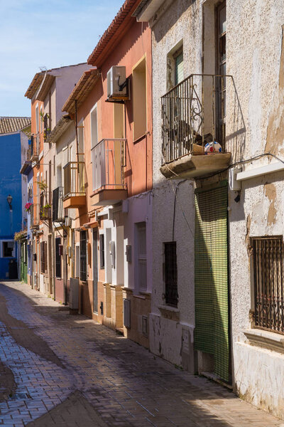Denia fishing quarter street with colorful Mediterranean old town houses and cobbelstone pavement